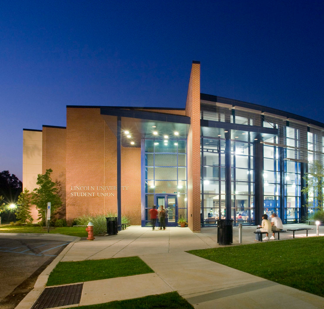 Student union building at night with people walking and sitting outside